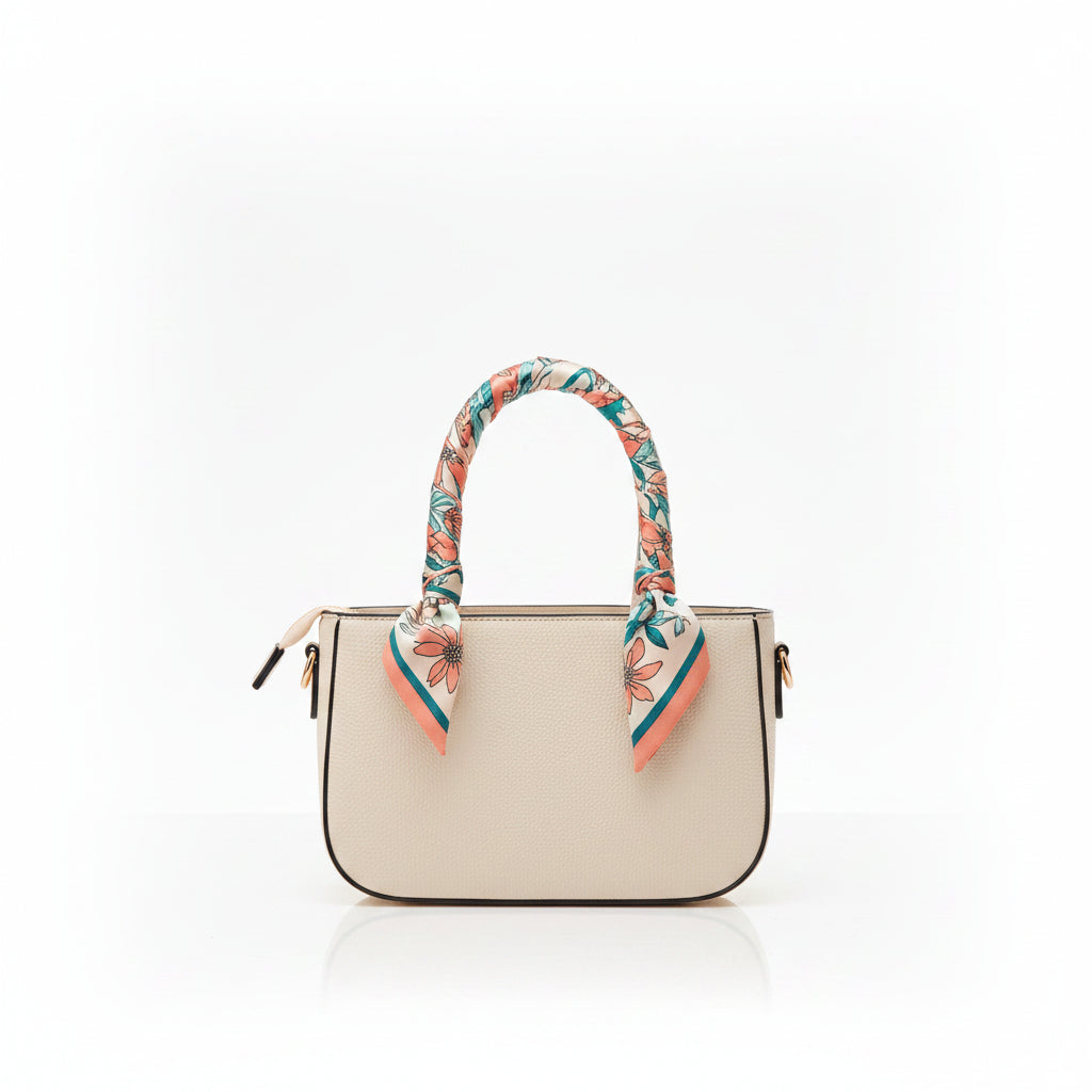 A structured cream-colored leather handbag with a floral-patterned scarf tied to its top handles, set against a plain white background.