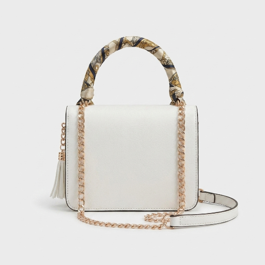 A structured white handbag shown from multiple angles on a clean white background, featuring a patterned scarf handle, gold-tone chain strap, tassel detail, and navy-and-gold scarf ends.
