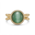 A gold ring featuring a large oval green cabochon gemstone surrounded by a halo of small clear stones, with a twisted gold band.