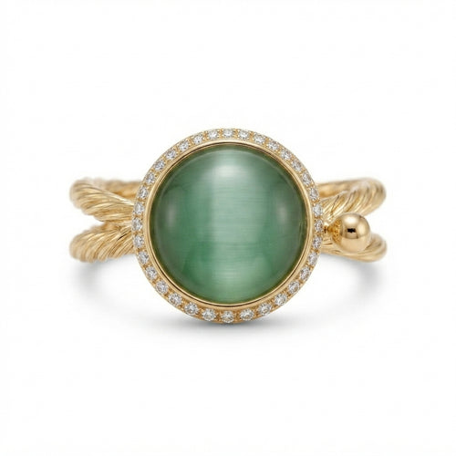 A gold ring featuring a large oval green cabochon gemstone surrounded by a halo of small clear stones, with a twisted gold band.