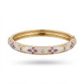 A gold-plated hinged bangle bracelet with a white enamel outer band decorated with purple floral motifs and small clear rhinestones, shown against a plain white background.