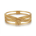 A gold multi-band bangle bracelet featuring a combination of smooth banded rings, twisted rope textures, and braided details, shown on a clean white background.