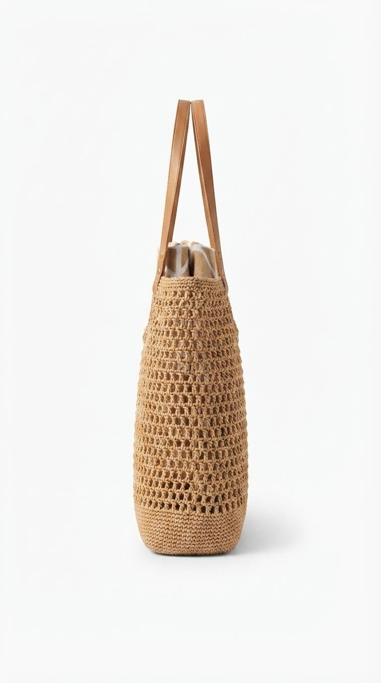 A natural woven straw tote bag with two tan shoulder straps, shown against a plain white background.