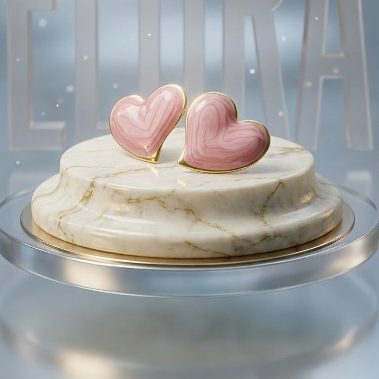 A round marble-patterned cake or decorative stand on a reflective surface, topped with two pink heart-shaped candies or toppers, against a soft blue-gray background with large translucent letters behind it.